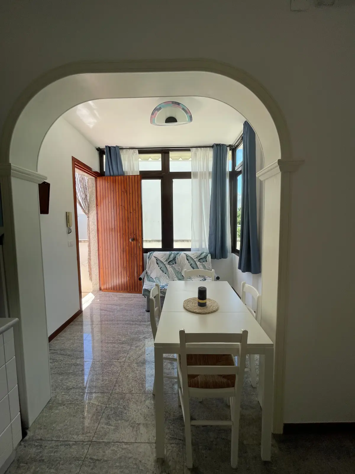 Zona pranzo con arco interno e tavolo bianco di Casa delle Ginestre